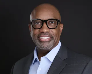 Professional executive headshot of man in charcoal suit and black glasses for LinkedIn profile Phoenix Arizona